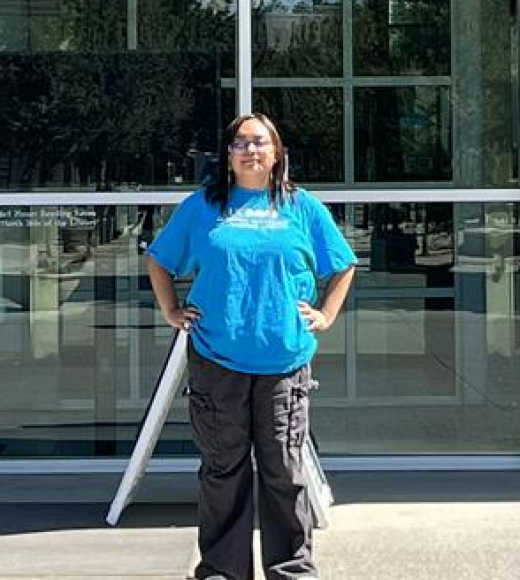 1 woman in blue shirt standing in front of library 