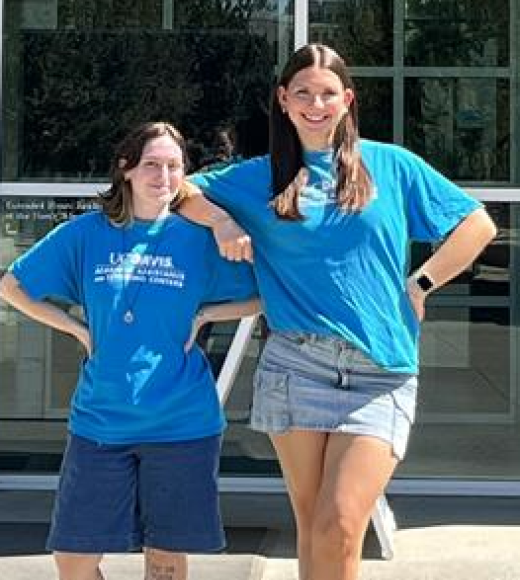 Two people standing in front of Library in Blue shirts 