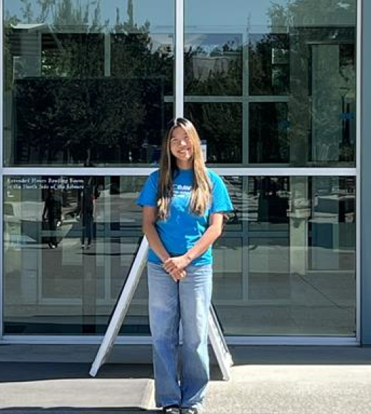 1 woman head subject tutor standing in front of library in blue shirt