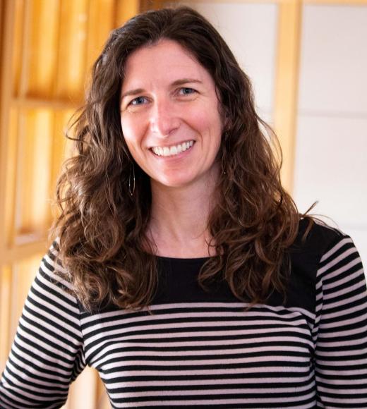 Ariel Loring smiling with face and torso in frame standing inside Dutton Hall with window in the background