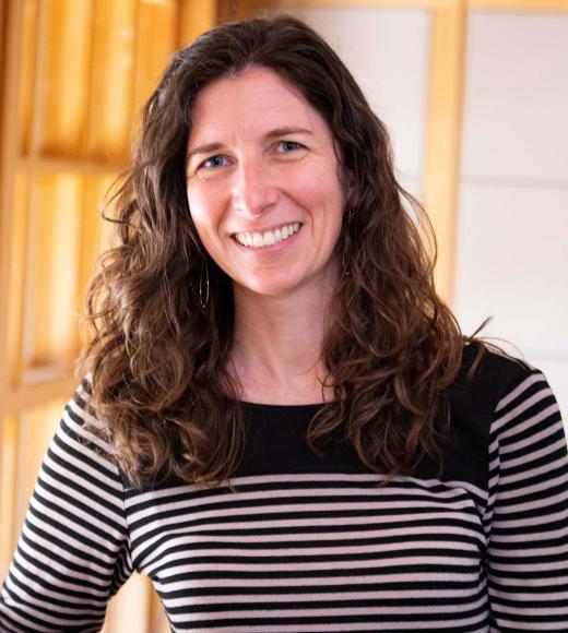 Ariel Loring smiling with face and torso in frame standing inside Dutton Hall with window in the background