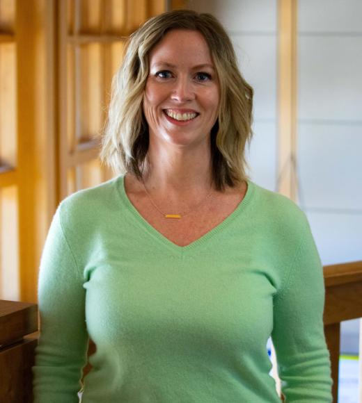 Bridget Mabunga smiling with face and torso in frame standing inside Dutton Hall with window in the background