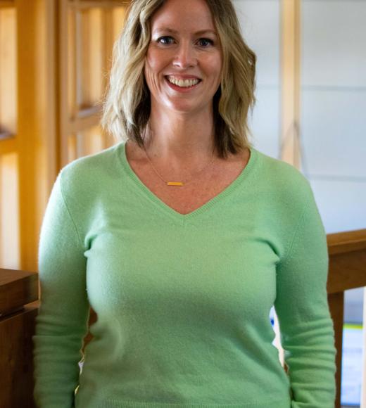 Bridget Mabunga smiling with face and torso in frame standing inside Dutton Hall with window in the background