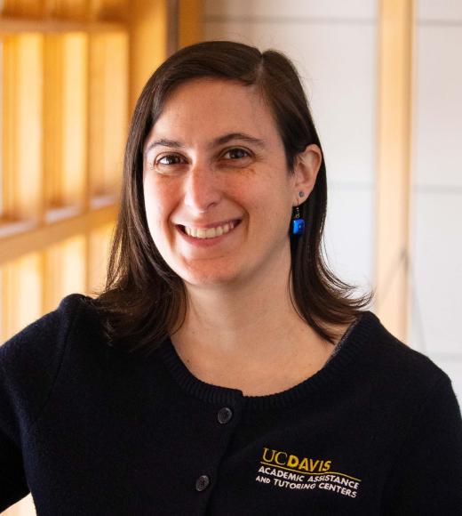 Heather Sturman smiling with face and torso in frame standing inside Dutton Hall with window in the background