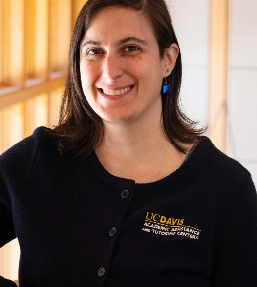 Heather Sturman smiling with face and torso in frame standing inside Dutton Hall with window in the background