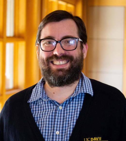 Kevin Sitz smiling with face and torso in frame standing inside Dutton Hall with window in the background